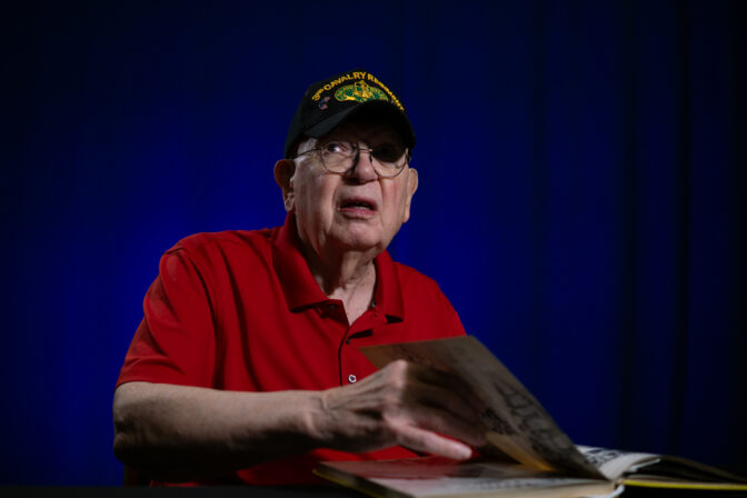 Tom Lambert looks through his unit's yearbook. (Jeremy Long - WITF)